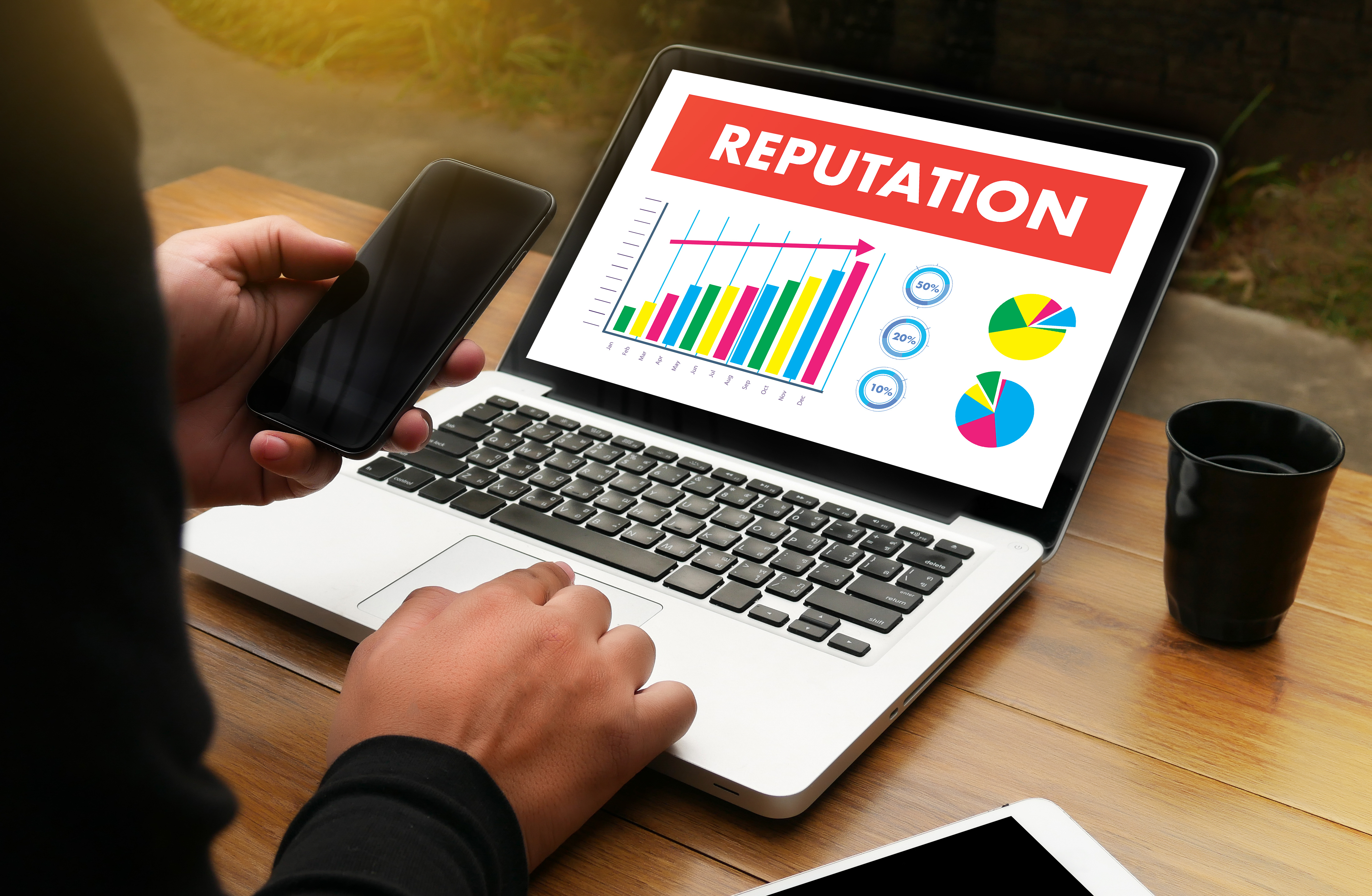 open laptop with the word reputation along with colorful graphs and charts on screen